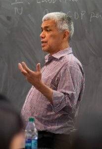 Behzad Diba in a maroon button down shirt, teaching in front of a chalkboard