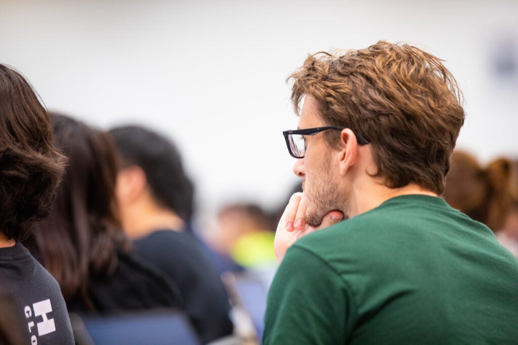 student in green shirt and glasses listening in class